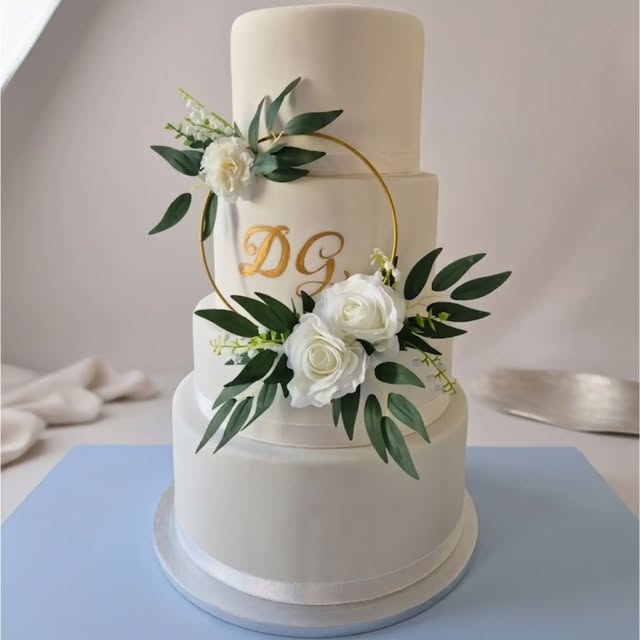 Torta bianca a più piani decorata con fiori e foglie verdi